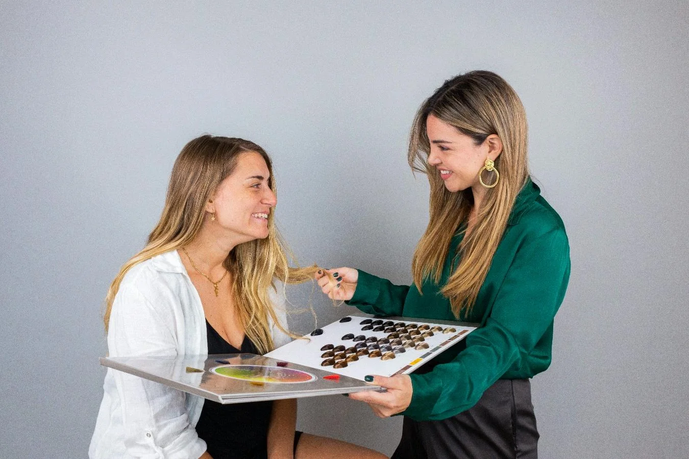 Asesora de imagen comparando el cabello de una clienta con una carta de tonos en un estudio