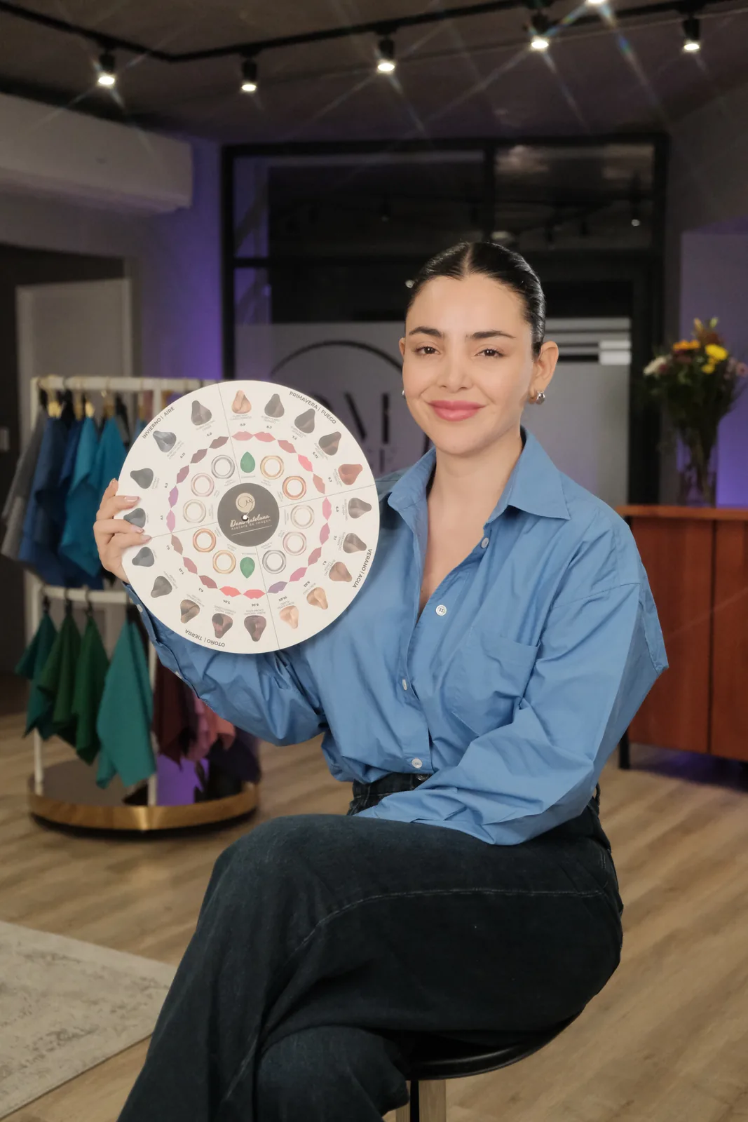 Daniela Mateluna mostrando un círculo cromático junto a percheros con ropa de colores